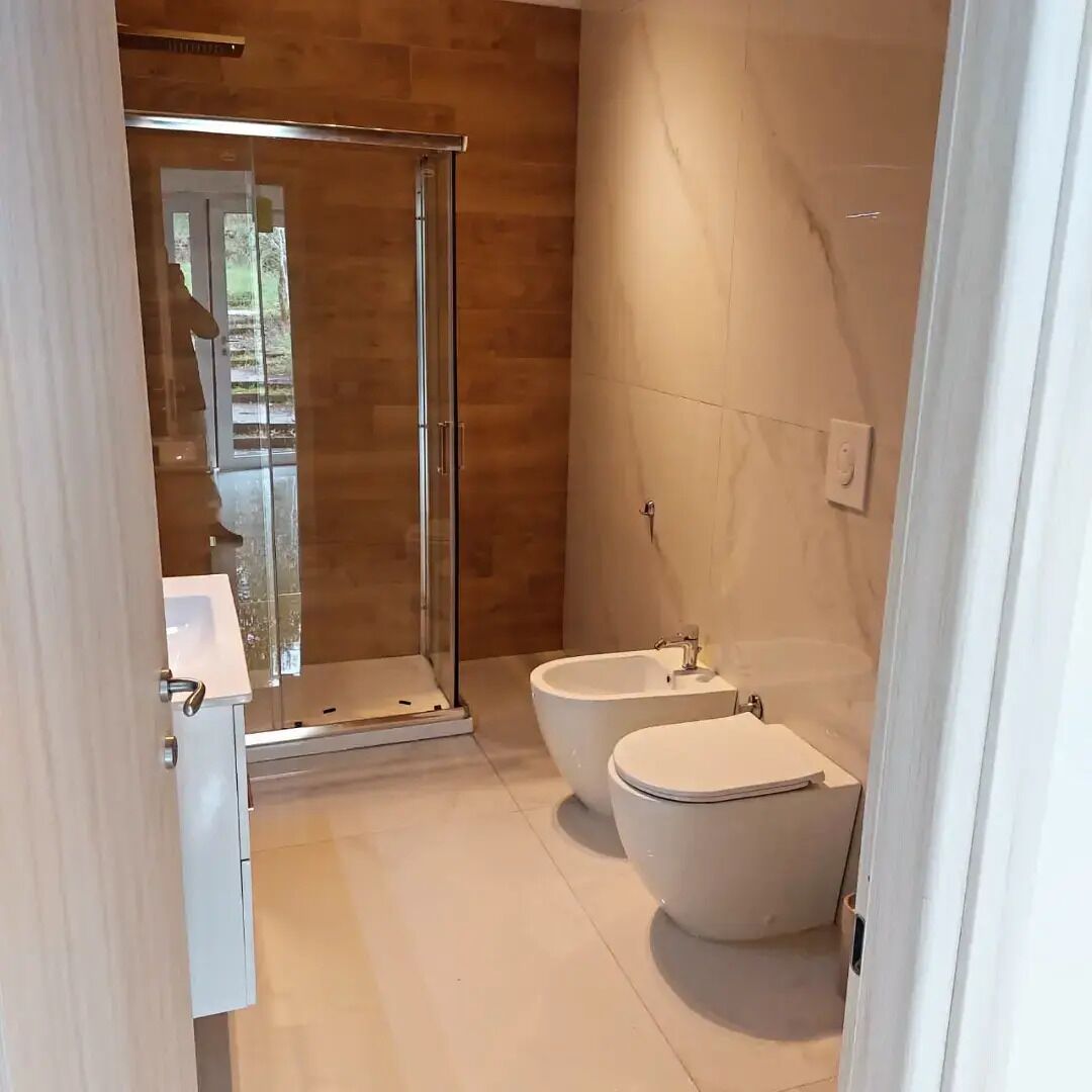 A modern bathroom with a glass-enclosed shower, a freestanding bathtub, and a toilet.