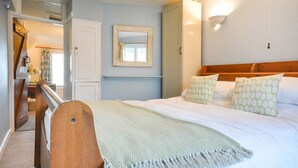 Un dormitorio con cama, cabecera de madera, espejo y lámpara de pared.