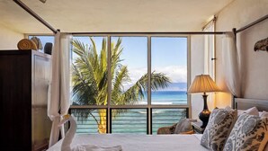 Ein Hotelzimmer mit einem großen Bett, einem schwanenförmigen Handtuch, einer Lampe und Blick aufs Meer.