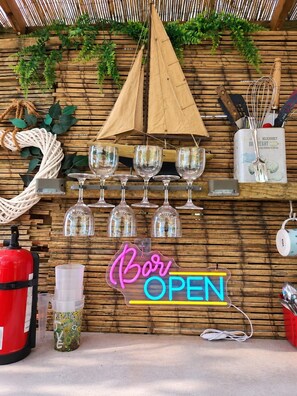 A bar area with a neon sign reading 'Bar OPEN,' glasses, a fire extinguisher, and a decorative rope. - The Riverside Retreat (GLOUCESTERSHIRE)