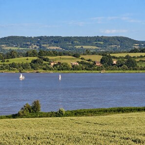 A lake with sailboats, surrounded by green fields and houses on the hills. - The Riverside Retreat (GLOUCESTERSHIRE)