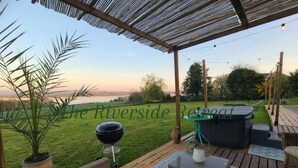 Una terrassa exterior amb mobles de vimetla, un barbacoa i una banyera d'hidromassatge.