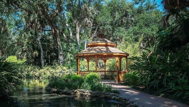 A wooden gazebo in a lush garden with a pond. - Beautiful New 4-BR Home Near All Major Attractions (Palm Coast)