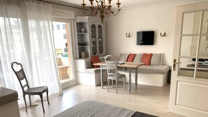 Ein Zimmer mit einem Bett, einem Esstisch mit Stühlen, einer Couch und einem an der Wand befestigten Fernseher.