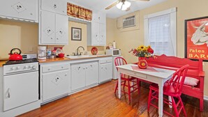 A kitchen with white cabinets, a red kettle, and a ceiling fan.