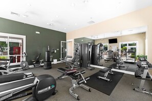 A gym with various exercise equipment, a mirrored wall, and a Coca-Cola advertisement. - Baytowne Wharf Condo-Large Private Balcony-Beach (Miramar Beach)