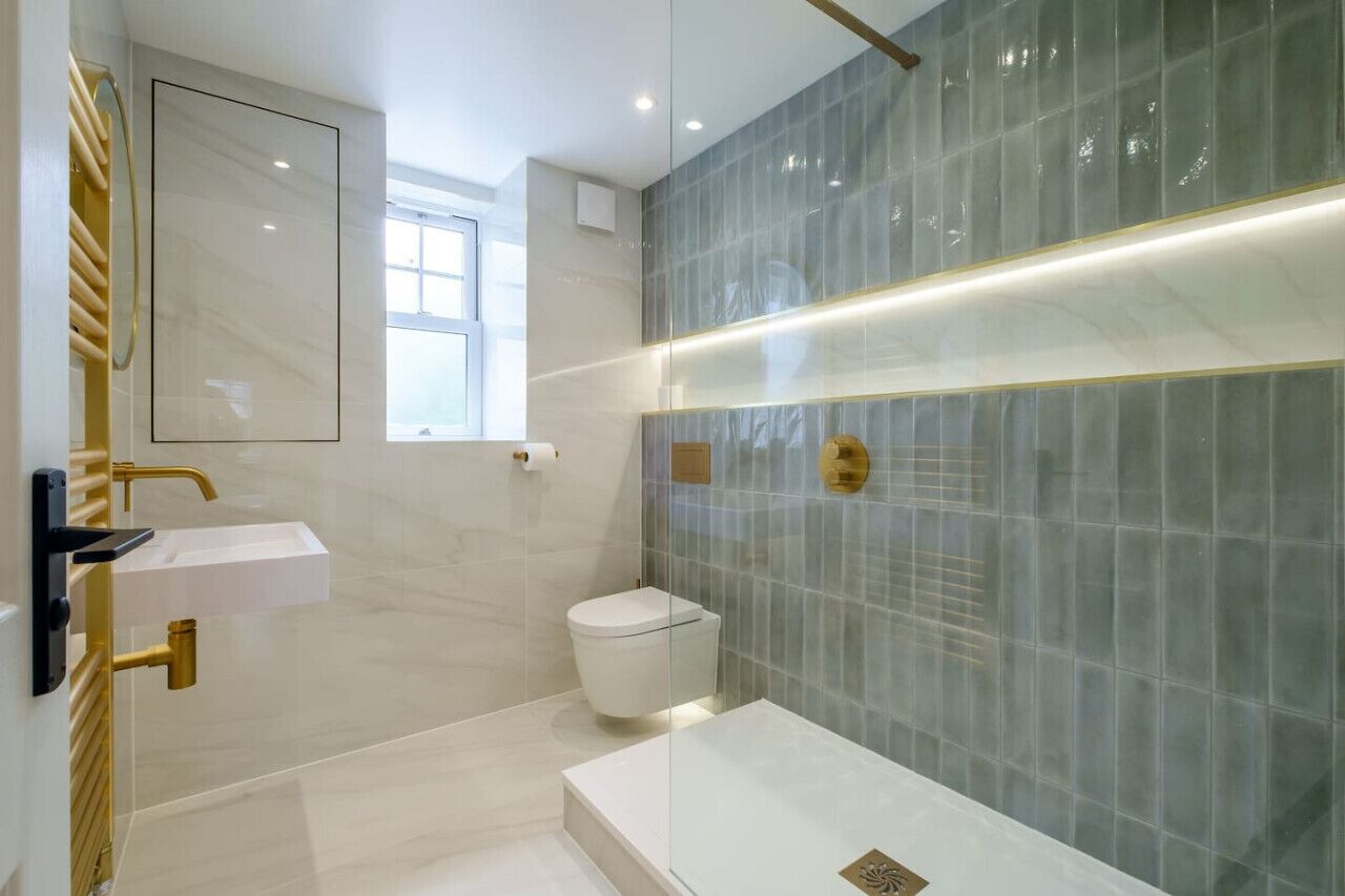 A modern bathroom with a white sink, gold fixtures, and a glass shower enclosure.