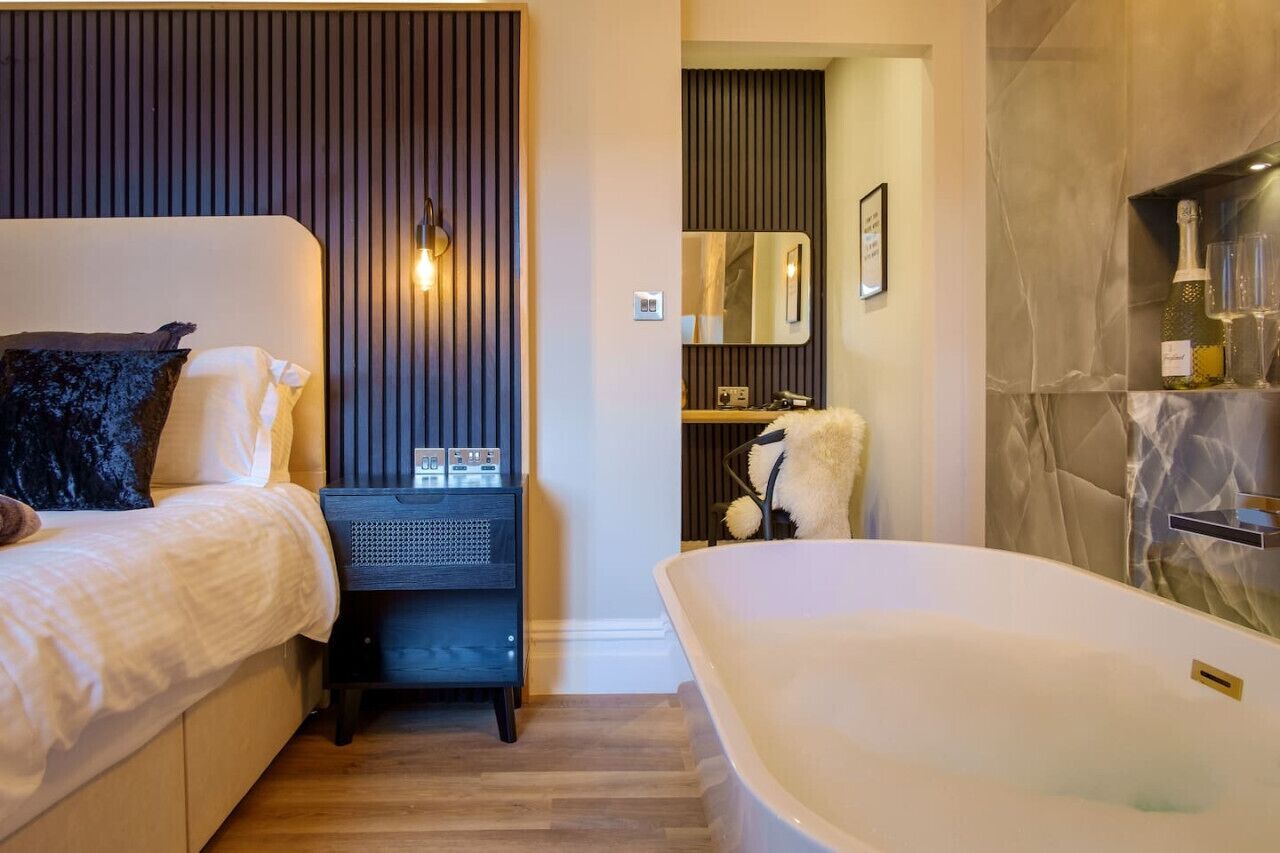 Une chambre à coucher moderne avec un lit, une table de chevet et une grande baignoire.