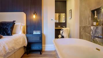Une chambre à coucher moderne avec un lit, une table de chevet et une grande baignoire.
