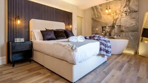 Ein modernes Schlafzimmer mit einem großen Bett, Nachttisch und einer integrierten Badewanne.