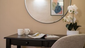 A room with a round mirror on the wall, a desk with a magazine, two white mugs, and a potted orchid. - Leven  The  Bowering (Cumbria)
