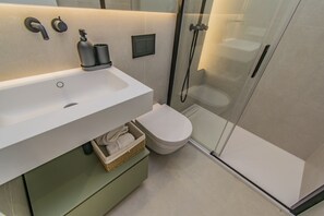 Ett modernt badrum med en vit tvättställ, en duschkabin med glasväggar och en toalett.