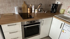 A compact kitchen with a built-in oven, a coffee maker, and a dishwasher.