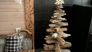 A room with a wooden Christmas tree made of logs and a decorative snowflake. - Ocean view guest suite, completely self contained, beautiful outdoor patio (Campbell River)