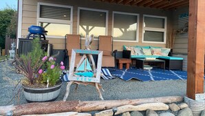 A covered outdoor seating area with a wooden pergola, a blue grill, and a rustic sign that reads "PASSAGE VIEW." - Ocean view guest suite, completely self contained, beautiful outdoor patio (Campbell River)