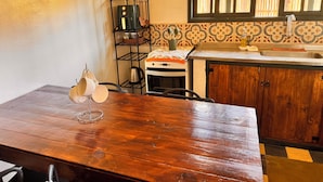 A kitchen with a wooden table, a coffee maker, a kettle, and a sink. - Refúgio dos pinhais (Sapucai-Mirim)