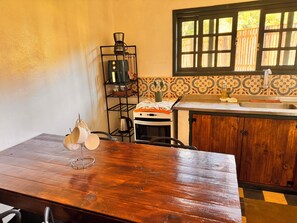 A kitchen with a wooden table, a coffee maker, a kettle, and a sink. - Refúgio dos pinhais (Sapucai-Mirim)