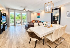 A modern living room with a dining area, a ceiling fan, and a view of the outdoors.