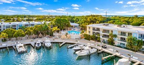 A marina with boats docked, a pool, and buildings with balconies overlooking the water.