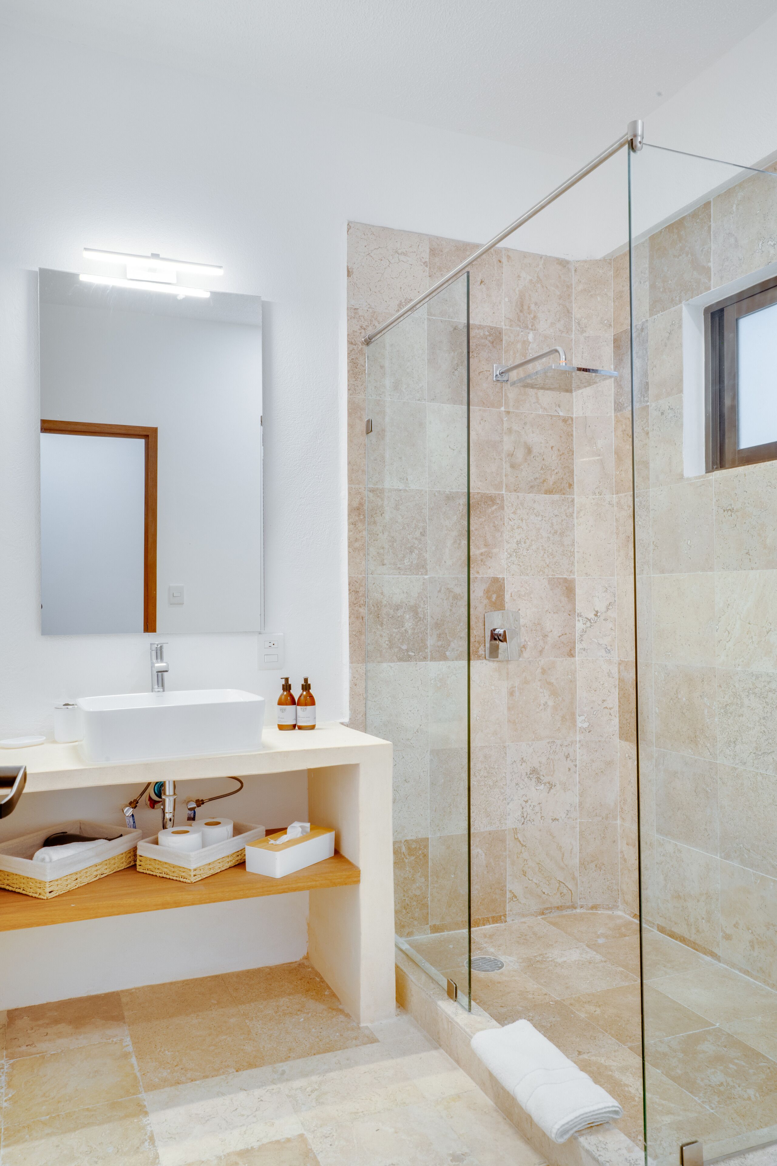A modern bathroom with a glass-enclosed shower, a white sink, and a mirror above it.
