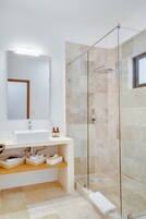 A modern bathroom with a glass-enclosed shower, a white sink, and a mirror above it.