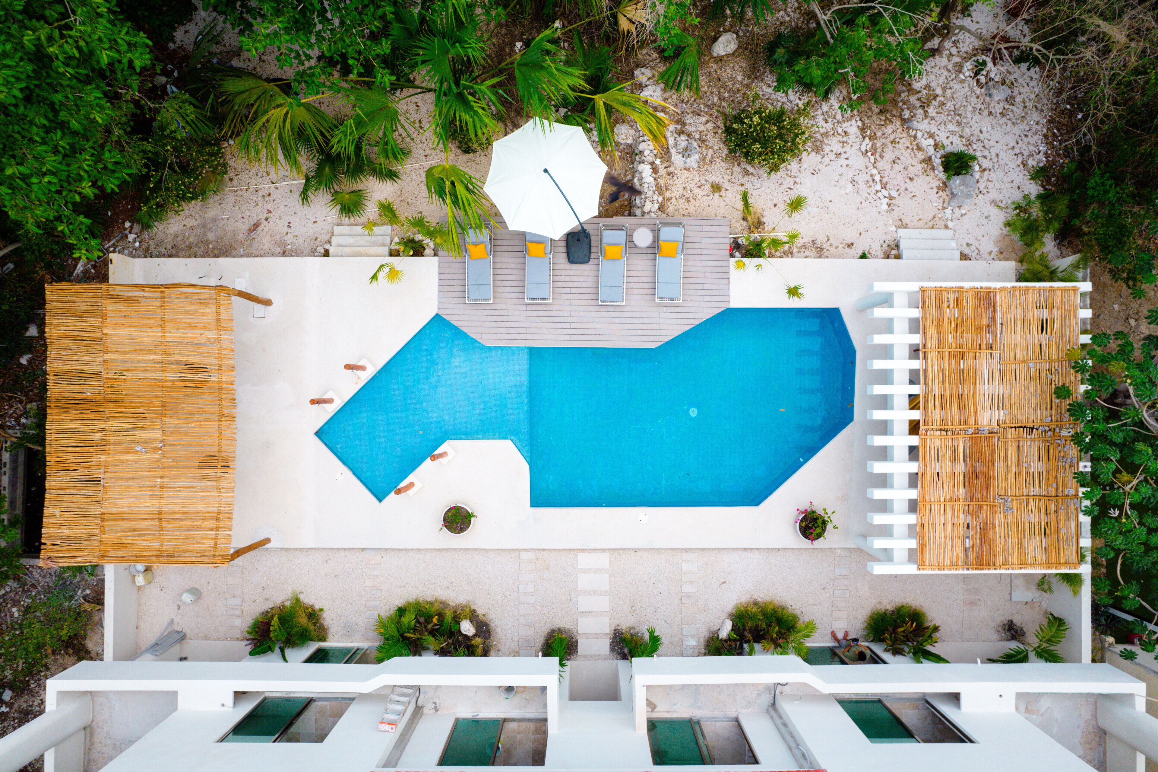 Vista aérea de un resort con una gran piscina, tumbonas y una zona de playa.
