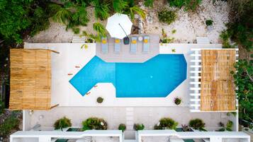 Vista aérea de un resort con una gran piscina, tumbonas y una zona de playa.