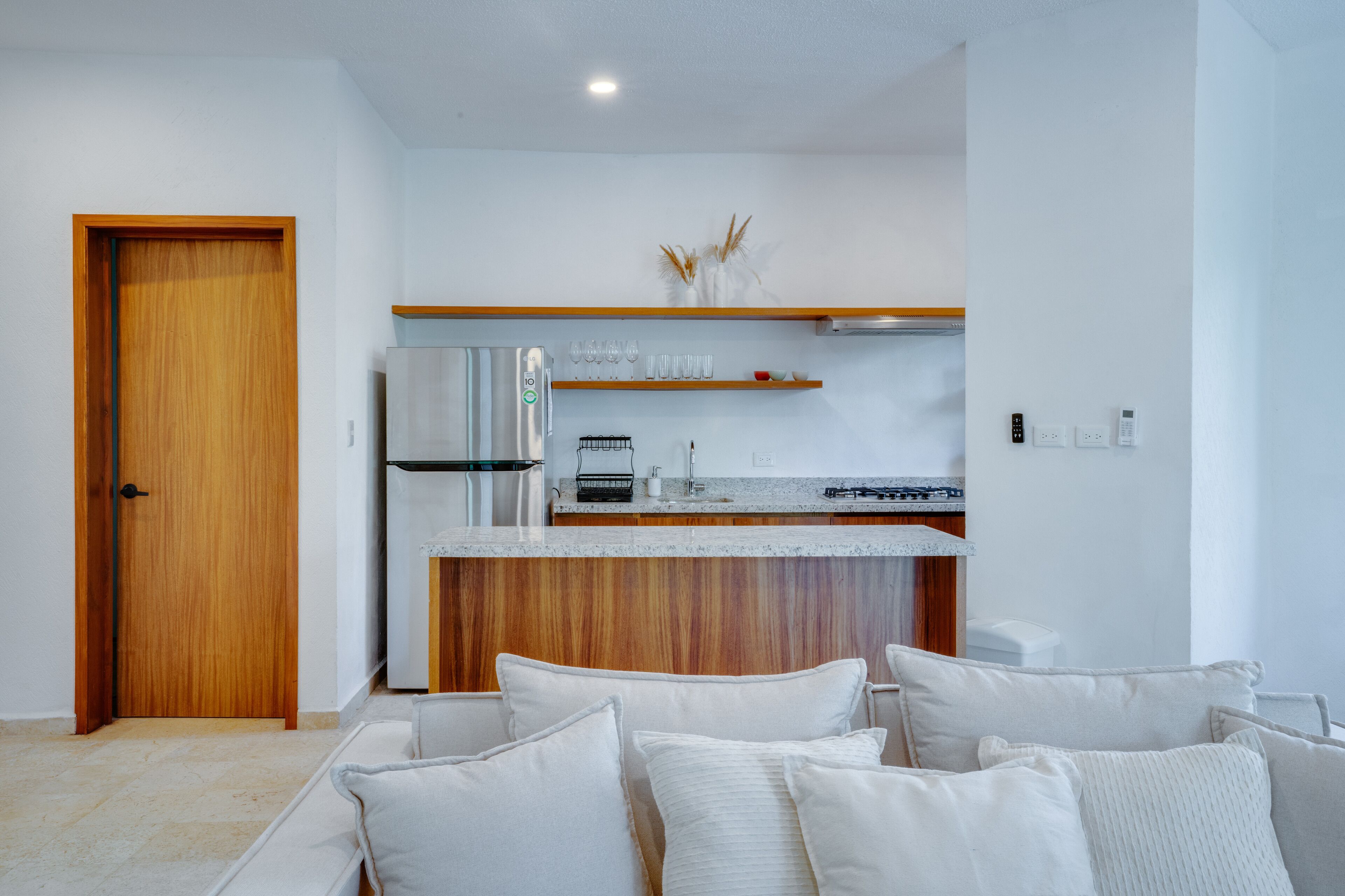 Une cuisine moderne avec une porte en bois, un réfrigérateur encastré et un plan de travail doté d’un évier et d’une cuisinière.