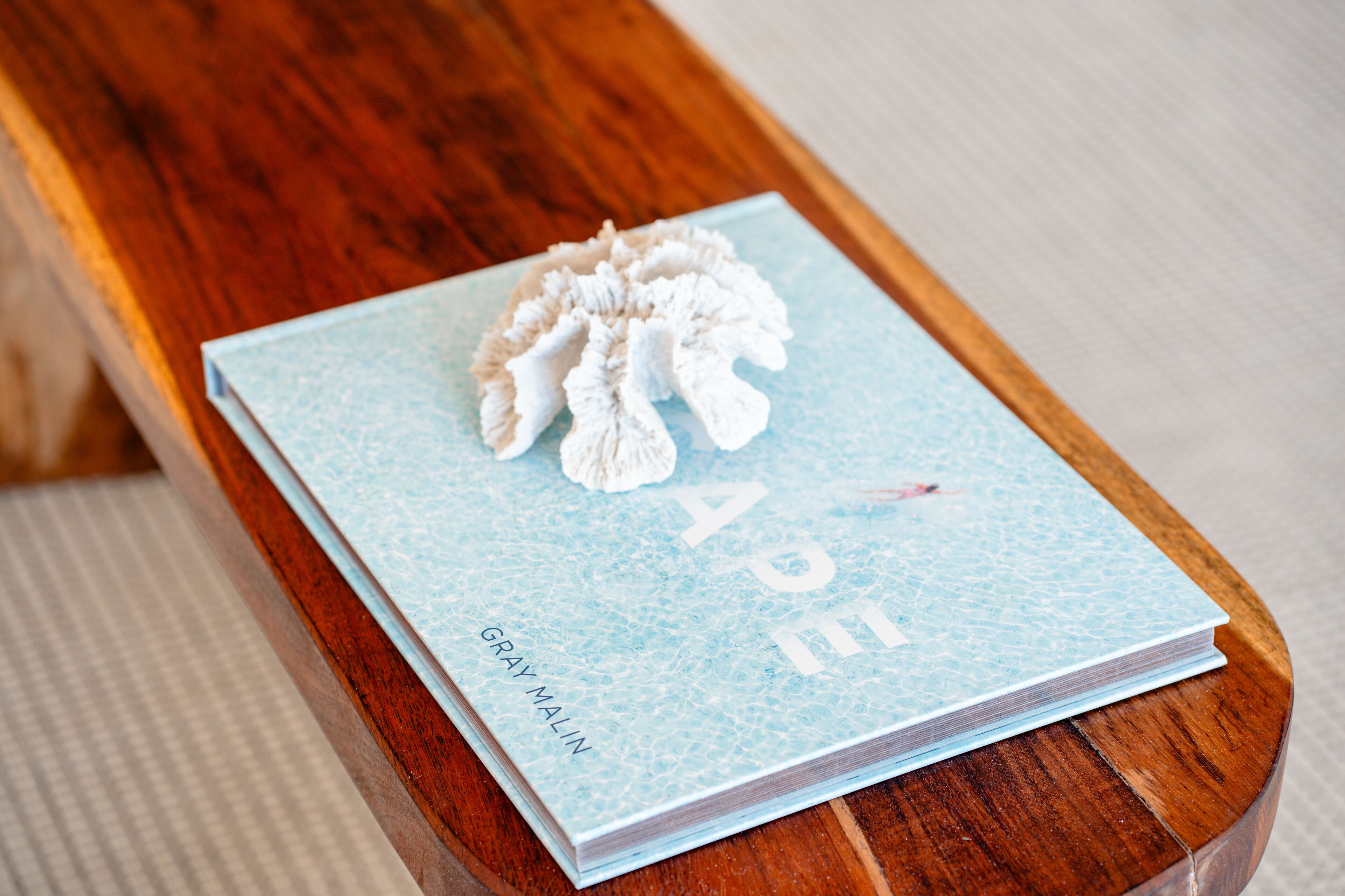 A book titled "APE" by Gray Malin on a wooden table.