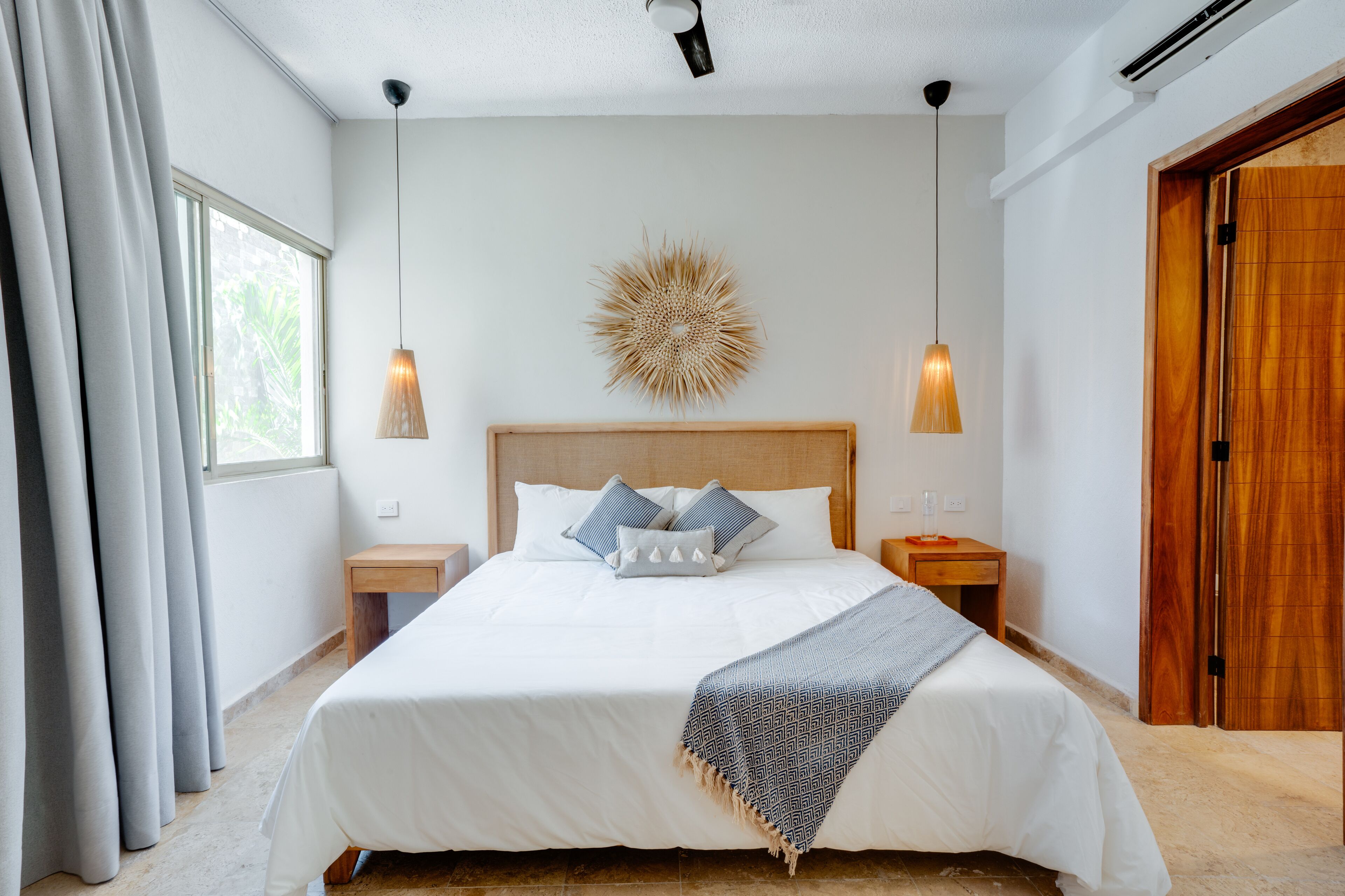 A neatly arranged bedroom with a large bed, two bedside tables, a decorative wall piece, and a wooden wardrobe.