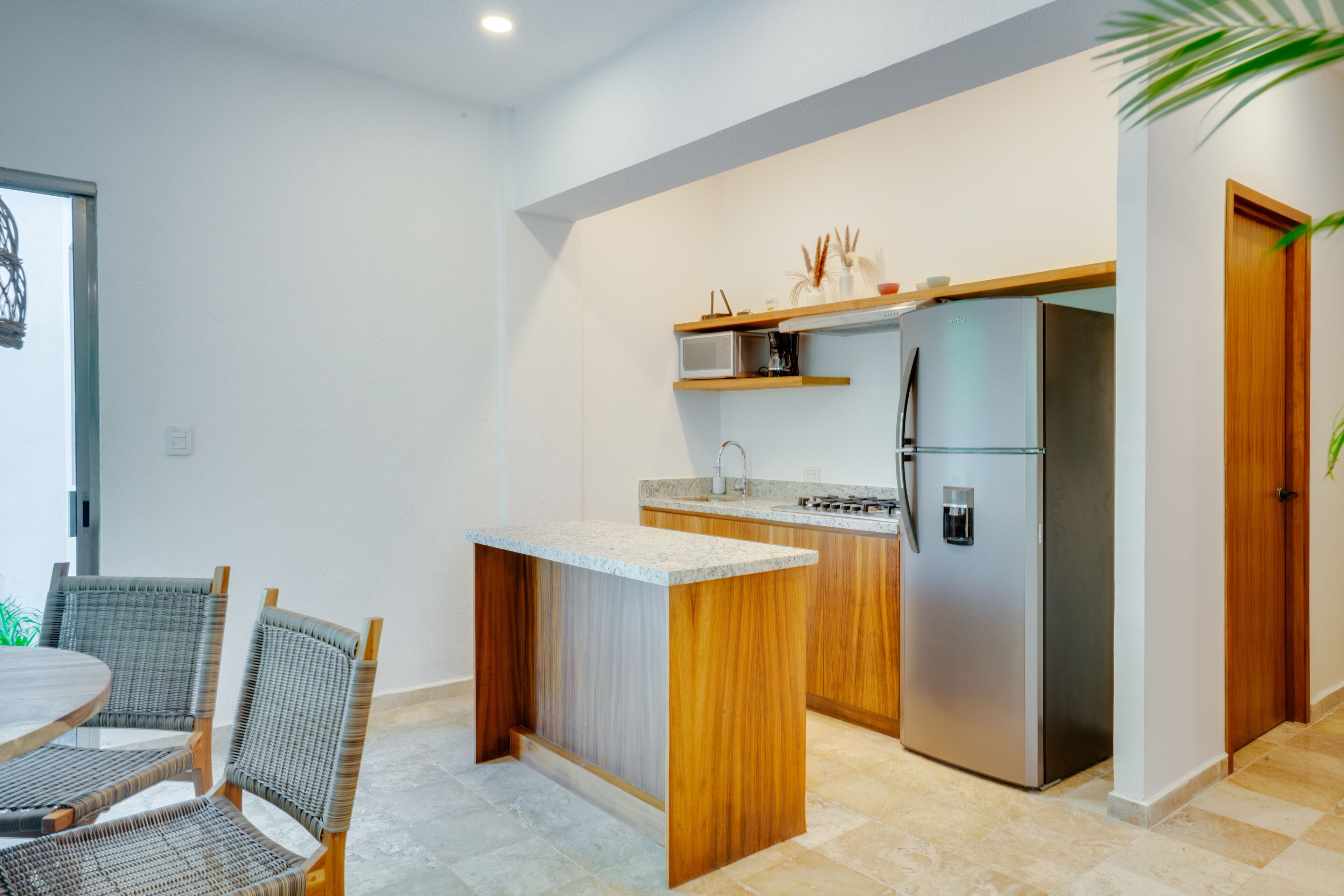 Una cocina moderna con una isla central, microondas integrado y refrigerador de acero inoxidable.