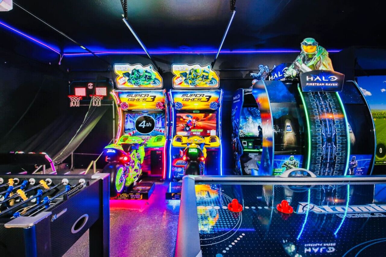 Una sala de juegos recreativos con varias máquinas de arcade, incluyendo una mesa de fútbol de mesa y una máquina temática de Halo.