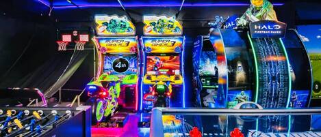 Una sala de juegos recreativos con varias máquinas de arcade, incluyendo una mesa de fútbol de mesa y una máquina temática de Halo.