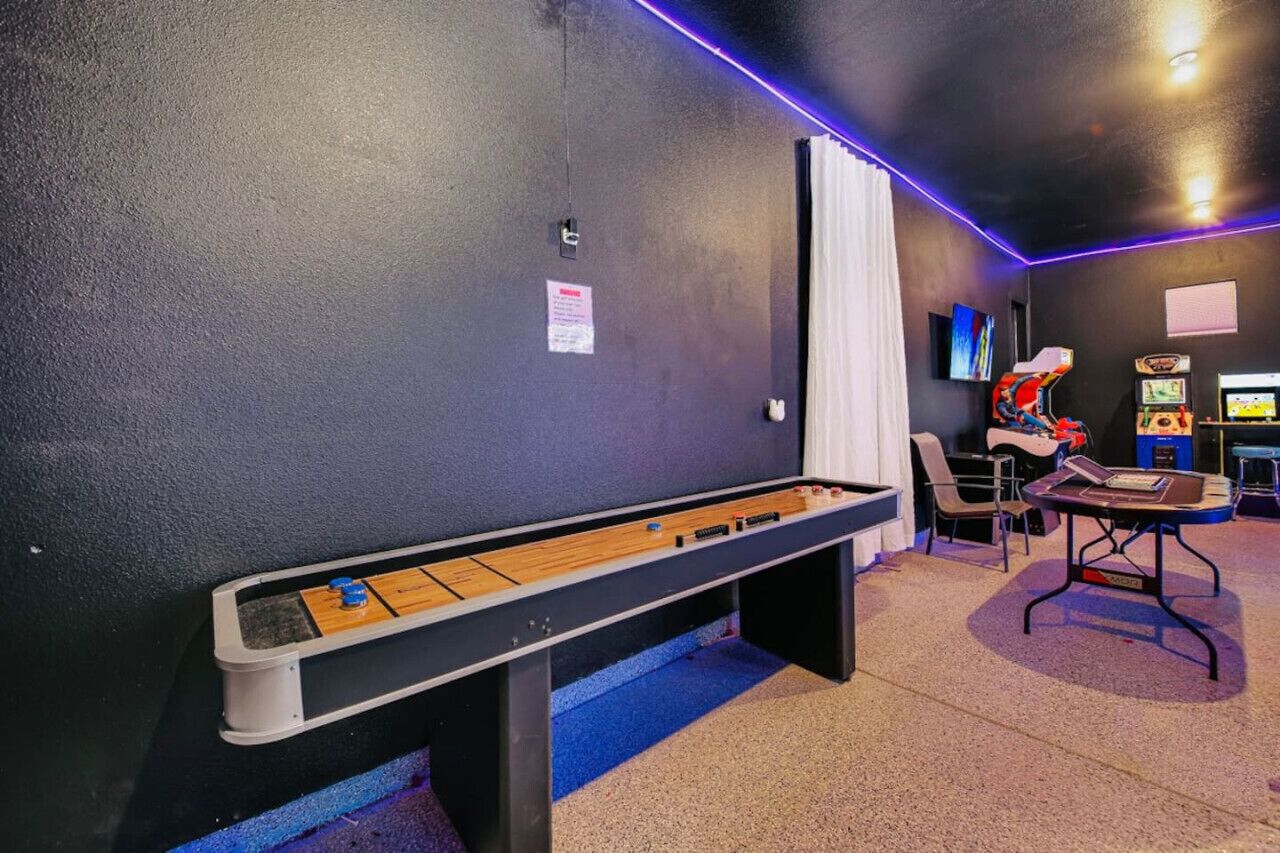 A room with a foosball table, a pool table, and arcade games.