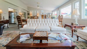 A spacious living room with a large white sofa, a wooden coffee table, and a patterned carpet. - Event Rental 10BR/10BA Sleeps 31 B&B Near The Lake (Marblehead)