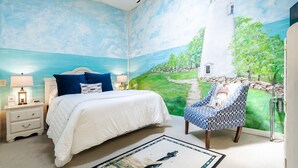 A bedroom with a mural of a lighthouse, a bed with white bedding, a blue chair, and a nightstand with a lamp. - Event Rental 10BR/10BA Sleeps 31 B&B Near The Lake (Marblehead)