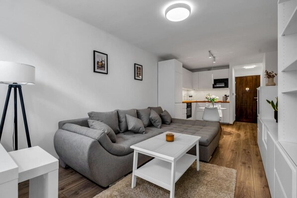 Ein modernes Wohnzimmer mit einem grauen Sofa, einem weißen Couchtisch und einer Stehlampe.