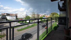 Ein Balkon mit Blick auf eine Stadtstraße, Gebäude und einen bewölkten Himmel.