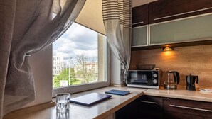Eine Küche mit Fenster, einer Mikrowelle, einem Wasserkocher und einem Notizbuch auf der Arbeitsplatte.