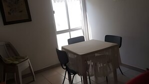 Ein Essbereich mit Tisch und Stühlen, einem Deckenventilator, einem Fenster mit Vorhängen und einem gerahmten Bild an der Wand.