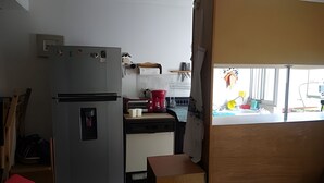 Eine kleine Küche mit einem Kühlschrank, einer Kaffeemaschine und einem Spülbecken.