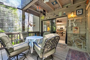 Relax on the patio with a round table and four chairs, surrounded by a wooden deck and stone wall.