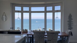 Una cocina moderna con tragaluces, ventanas amplias con vistas al océano y un comedor con sillas y mesa.