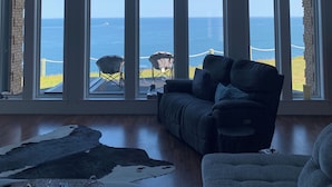 Una habitación con amplios ventanales de arco que dan al océano, un sofá de cuero y una alfombra.