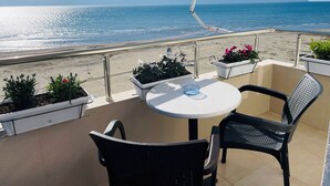 Un balcone con tavolo e sedie, piante in vaso e vista sul mare e sulle montagne.