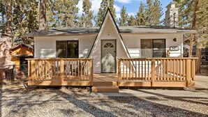 A cabin with a front porch, a chimney, and a small attached structure.