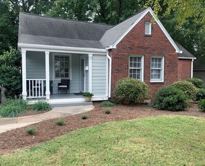 Charming single-story home with a front porch, entryway, and well-manicured lawn.
