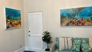 A room with a door, a plant, and a sofa with floral cushions. - Downtown Nassau Oasis: Unit 1 (Nassau)