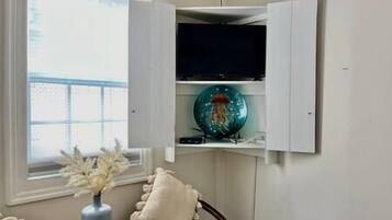 Een kamer met een wit kastje met een televisie en decoratieve spullen.