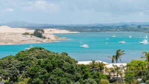 A coastal view with boats on turquoise waters, sandy beaches, and greenery. - Pearls Embrace - Mangawhai Heads Studio (Mangawhai Heads)
